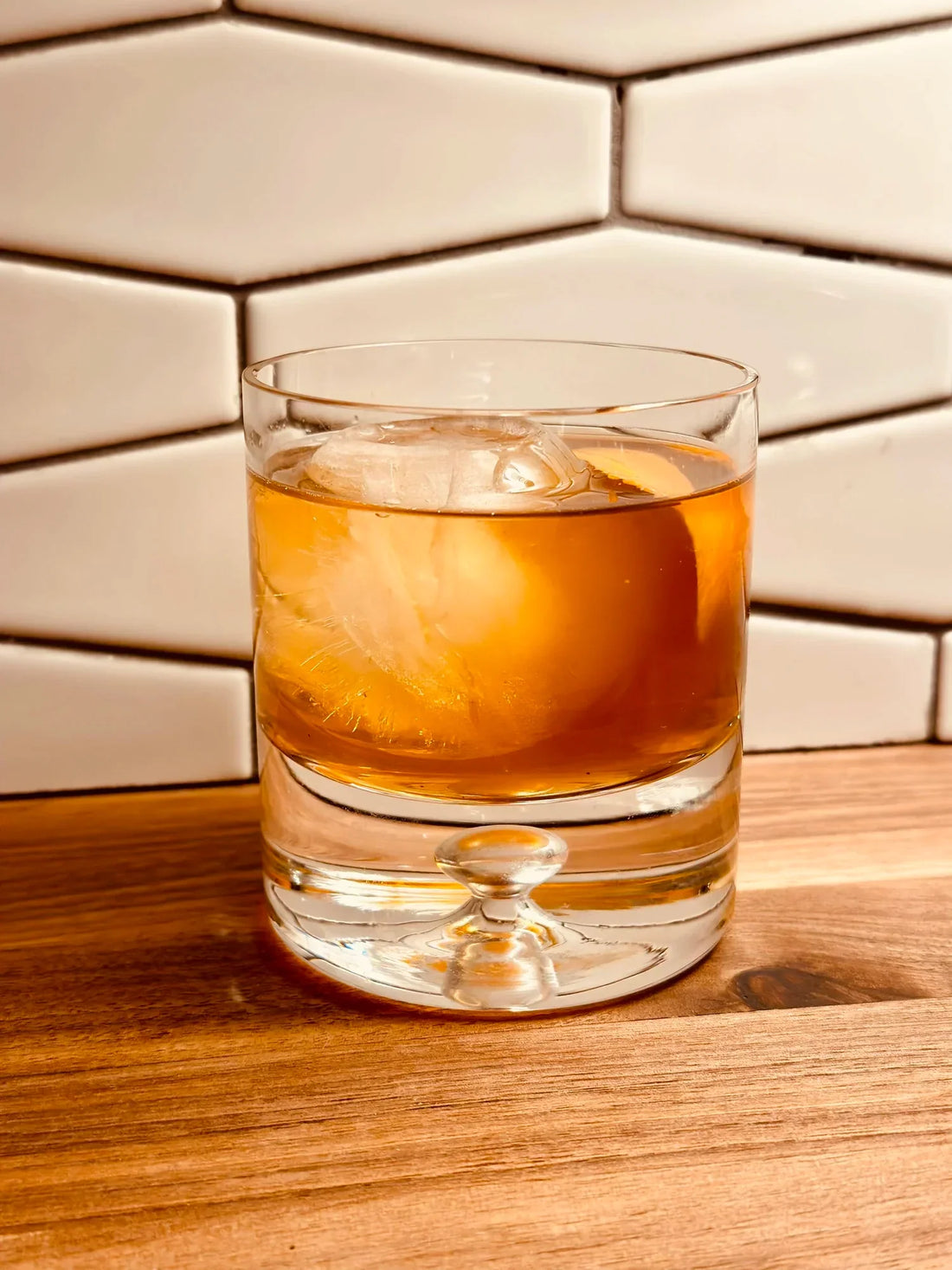 VANILLA OLD FASHIONED cocktail served in a glass with ice and a wooden background.