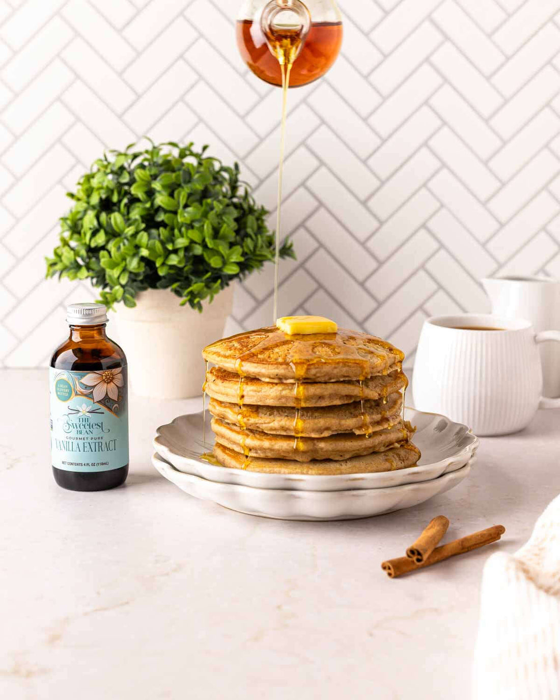 Delicious Vanilla Cinnamon Pancakes drizzled with syrup and served with a touch of butter.